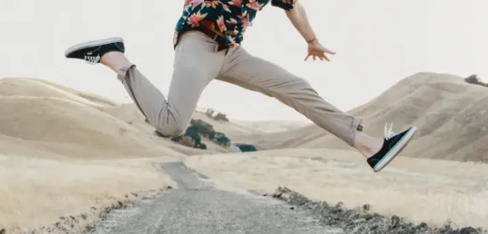 A man leaping across a path between two hills