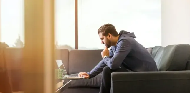 A person working on a laptop on a couch